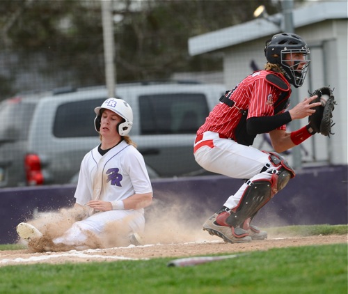 Recovery's Cade Wendel slides past St. Henry catcher Connor Bruggeman for a first inning run.