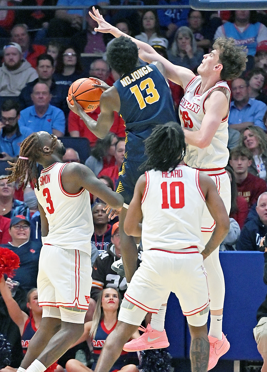 UD's swarming defenwe, led by Amael L'Etang, surrounds Canisius shooter.